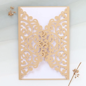 Macro view of laser-cut champagne gold wedding invitation with elegant scroll patterns