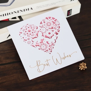 Detail of laser-cut heart and butterfly pattern on white greeting card with Best Wishes text