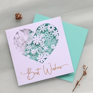 Macro shot of laser-cut heart pattern with floral butterfly details and gold foil lettering