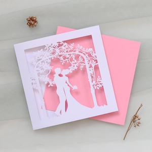 Detail of laser-cut wedding invitation featuring a couple silhouette and floral patterns