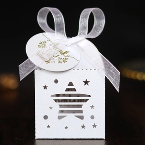 White laser-cut star candy box with ribbon and Thank You tag on dark background