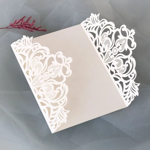 Détail de l'invitation ivoire découpée au laser avec dentelle florale et cœurs