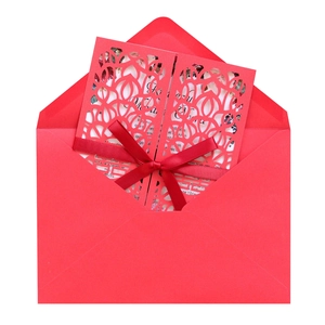Detailed laser-cut red wedding invitation with silk bow and floral interior card