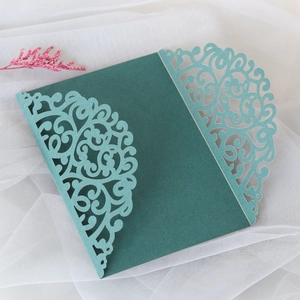 Detail of laser-cut vine patterns on a dark green and teal wedding invitation cover