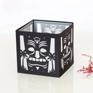 Detail of laser-cut black Tiki mask paper lantern with palm tree patterns and hollow design