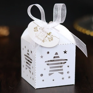 Close-up of white laser-cut star gift box with ribbon and gold Thank You tag
