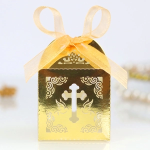 Detail of gold laser-cut candy box featuring a cross pattern and yellow organza ribbon