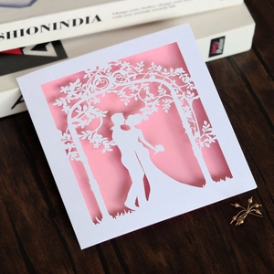 Detail of laser cut wedding invitation showing romantic couple silhouette and floral arch