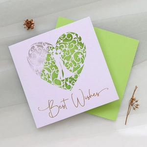 Detail of laser-cut heart pattern wedding card with golden Best Wishes text and green envelope