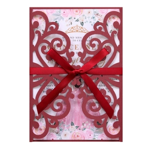 Macro detail of laser-cut burgundy invitation cover with elegant satin bow and floral insert