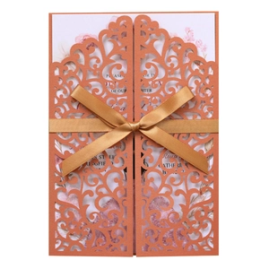 Detail of laser-cut orange invitation with golden satin bow and floral inner card