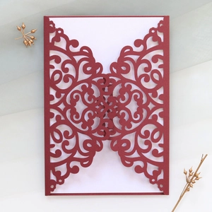 Detailed laser-cut vine pattern on burgundy wedding invitation with white insert