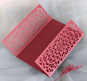 Intricate laser-cut patterns on red wedding invitation with traditional Double Happiness logo