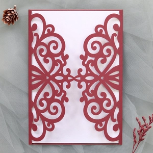 Detailed close-up of intricate laser-cut floral patterns on a red wedding invitation cover