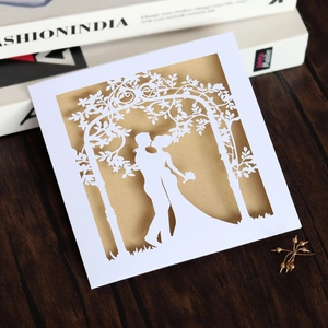 Detail of laser-cut wedding invitation showing romantic couple silhouette on white card