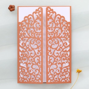 Detail of rose gold laser-cut wedding invitation cover with intricate scroll patterns
