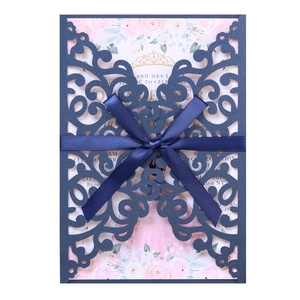 Detail of navy blue laser cut wedding invitation with satin bow and floral inner card