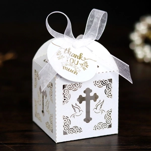 Detail of white laser-cut favor box with cross and dove patterns for weddings