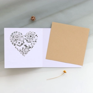 Detail of laser cut lace heart invitation card with kraft paper insert and butterfly