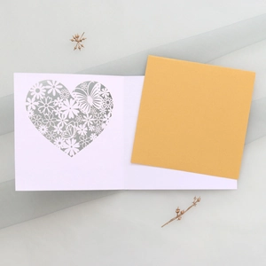 Detail of laser-cut butterfly heart card with gold insert on a textured background