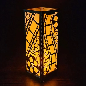 Movie themed film reel paper lantern with warm orange light on dark wood surface
