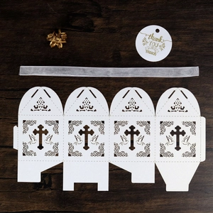 Detailed laser cut white cross and dove pattern on gift box with silver ribbon and tag