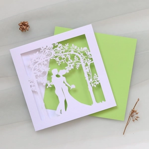 Detail of laser-cut wedding invitation featuring a romantic couple silhouette on white paper