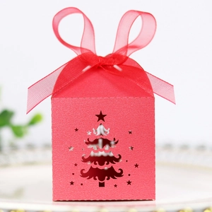 Detail of red Christmas gift box with laser-cut tree design and glossy ribbon bow