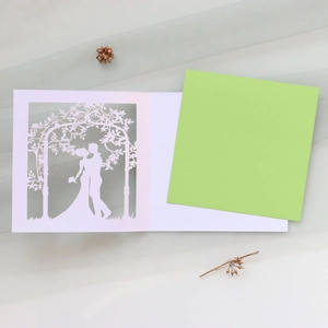 Detail of laser-cut wedding invitation showing bride and groom silhouette under flower arch