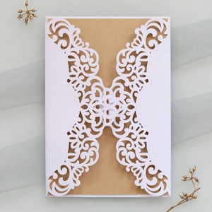 Detail of laser-cut hollow white invitation cover with kraft paper card insert