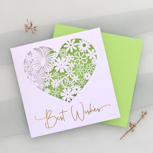 Detail showing white laser-cut heart pattern card with Best Wishes gold stamping and green envelope