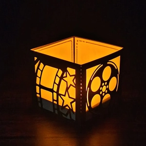 Macro view of film-themed black lantern with movie reel cutout and warm yellow light