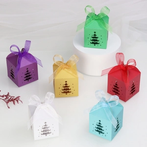 Close-up of festive paper candy boxes with laser-cut Christmas trees and organza ribbons