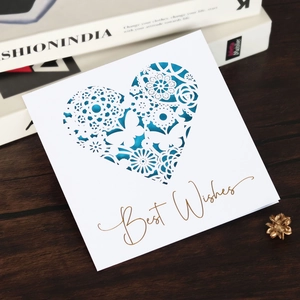 Detail of laser-cut heart pattern greeting card with golden Best Wishes text on wood