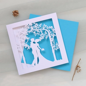 Close-up of laser-cut wedding invitation featuring a romantic couple silhouette
