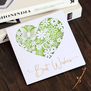 Detail of laser-cut heart greeting card with butterfly patterns and gold Best Wishes text