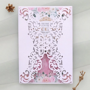 Close-up of laser-cut white wedding invitation with intricate lace crown patterns