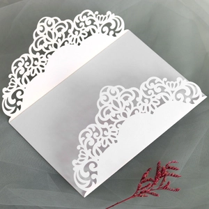 Close-up of white laser-cut wedding invitation with floral scrolls and vellum paper