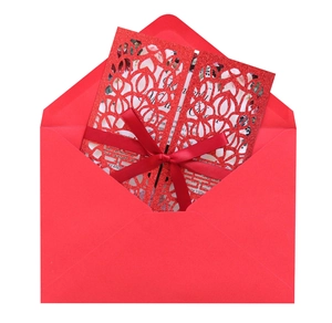Detail of red laser-cut wedding invitation with glitter finish and satin ribbon bow