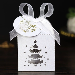 Macro view of white laser-cut Christmas tree gift box with ribbon and thank you tag