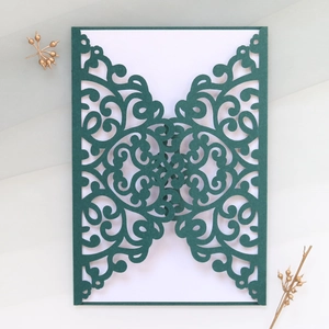 Detail showing dark green laser-cut wedding invitation cover with intricate vine patterns