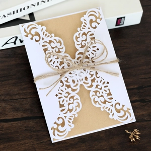 Detail of laser-cut hollow wedding invitation with kraft paper and rustic twine bow