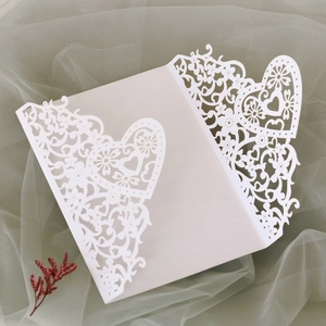 Detailed laser-cut white heart pattern on a wedding invitation cover with floral motifs