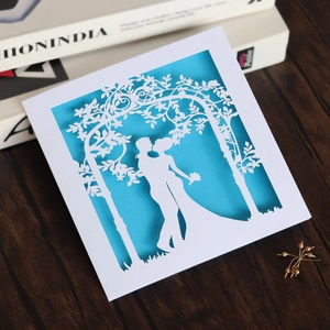 Detail of laser-cut floral arch and kissing couple on white and blue wedding invitation