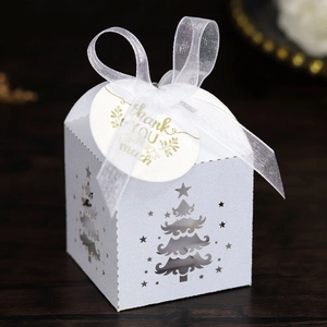 Detail of laser-cut Christmas tree candy box with white organza ribbon and gold thank you tag
