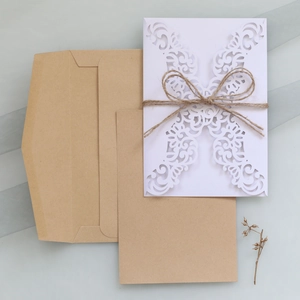 Close-up of laser-cut wedding invitation set with Kraft paper envelope and twine bow