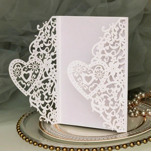 Detailed laser-cut heart and floral patterns on elegant white pearlescent wedding invitation