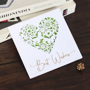 Detail of laser-cut white card with butterfly and heart patterns and gold Best Wishes text