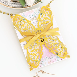 Detail of laser-cut gold butterfly invitation with pink floral patterns and a silk bow
