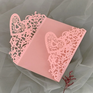 Detailed laser-cut wedding invitation sleeve with heart and floral vine patterns